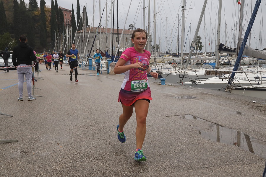 Biegnąc kobieta wzdłuż portu - na trasie Garda Trentino Half Marathon